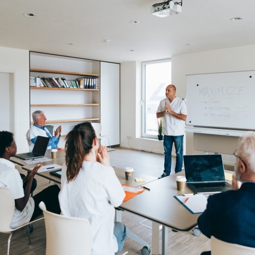 professional team of doctors attending a business presentation in a modern office, with a speaker explaining strategies on a whiteboard